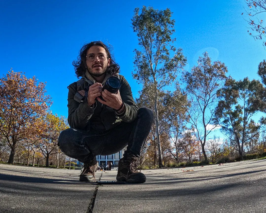 Cam, founder of Magic Films Media, crouching with a camera on location in Melbourne