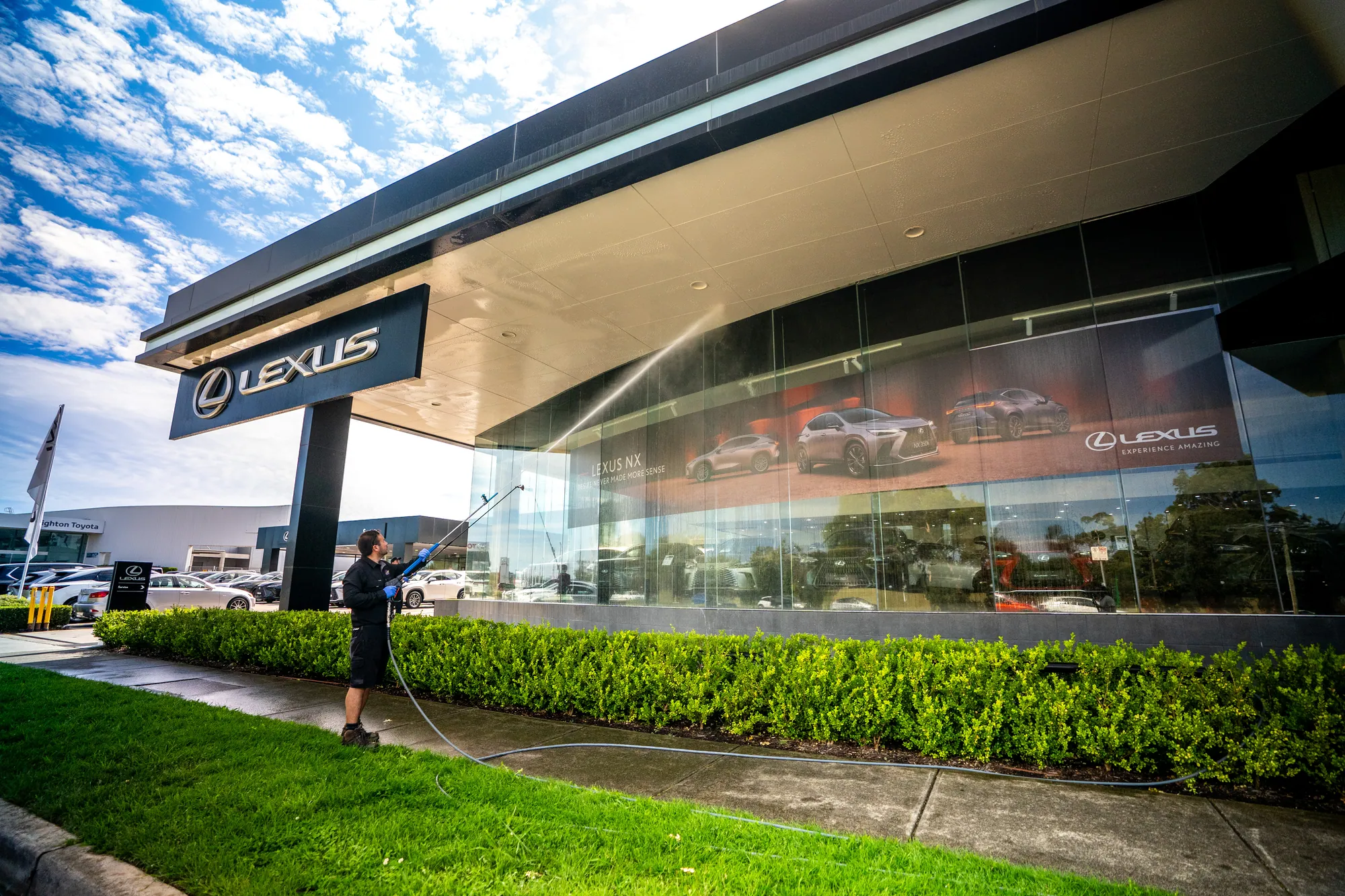 Pressure washing the front of a car dealership