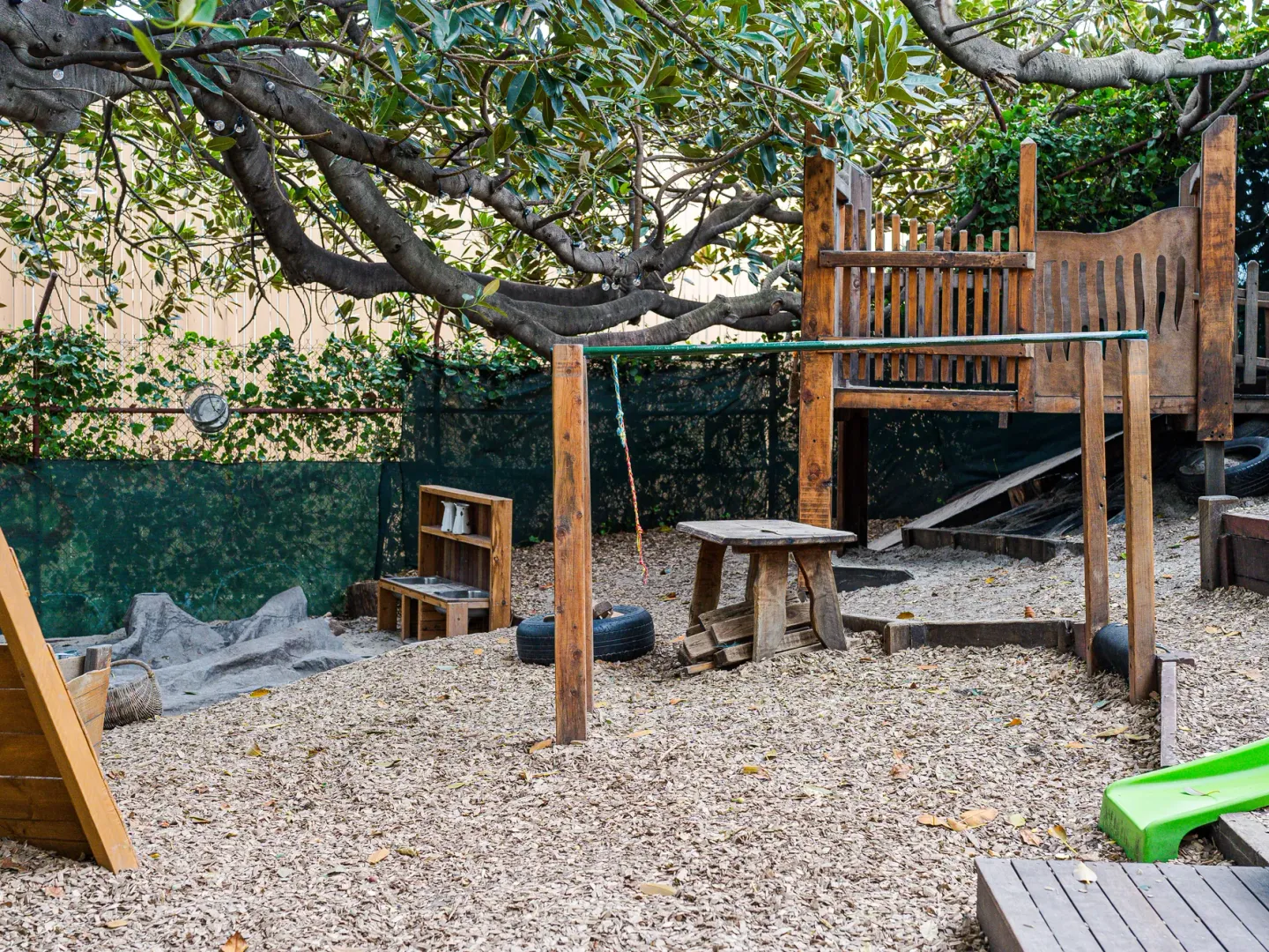 A natural playground with timber climbing frames under a big tree