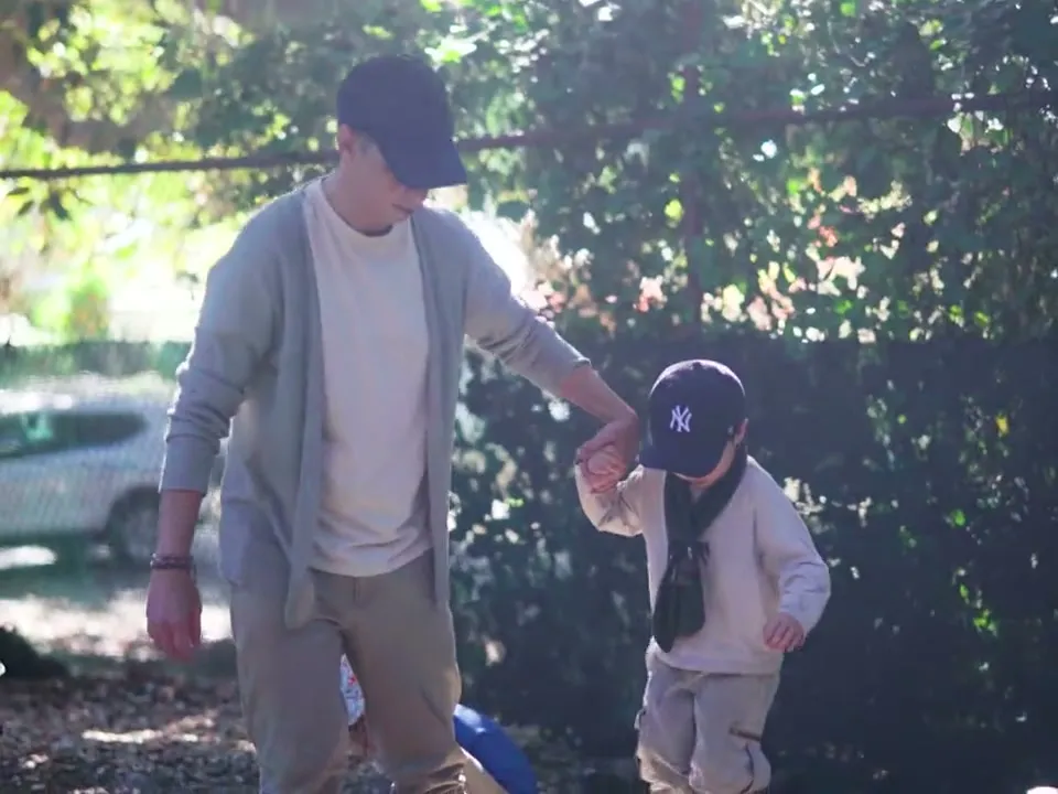 An educator walking hand in hand with a child through the garden