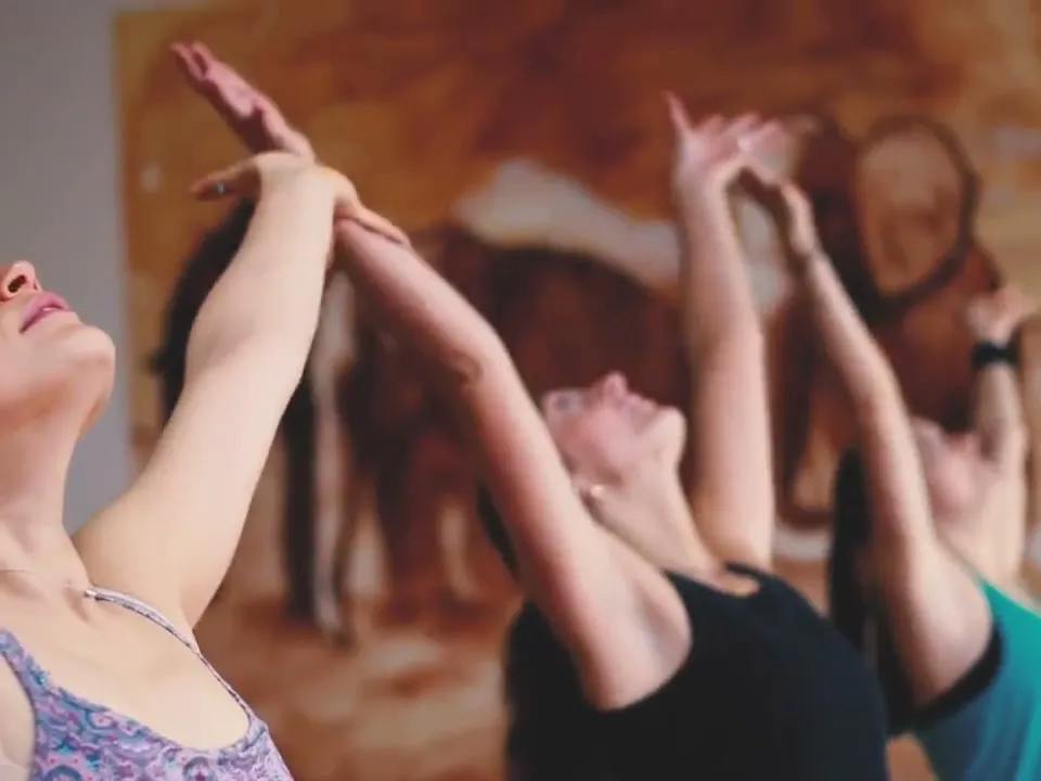 Yoga class reaching up together in a warm studio