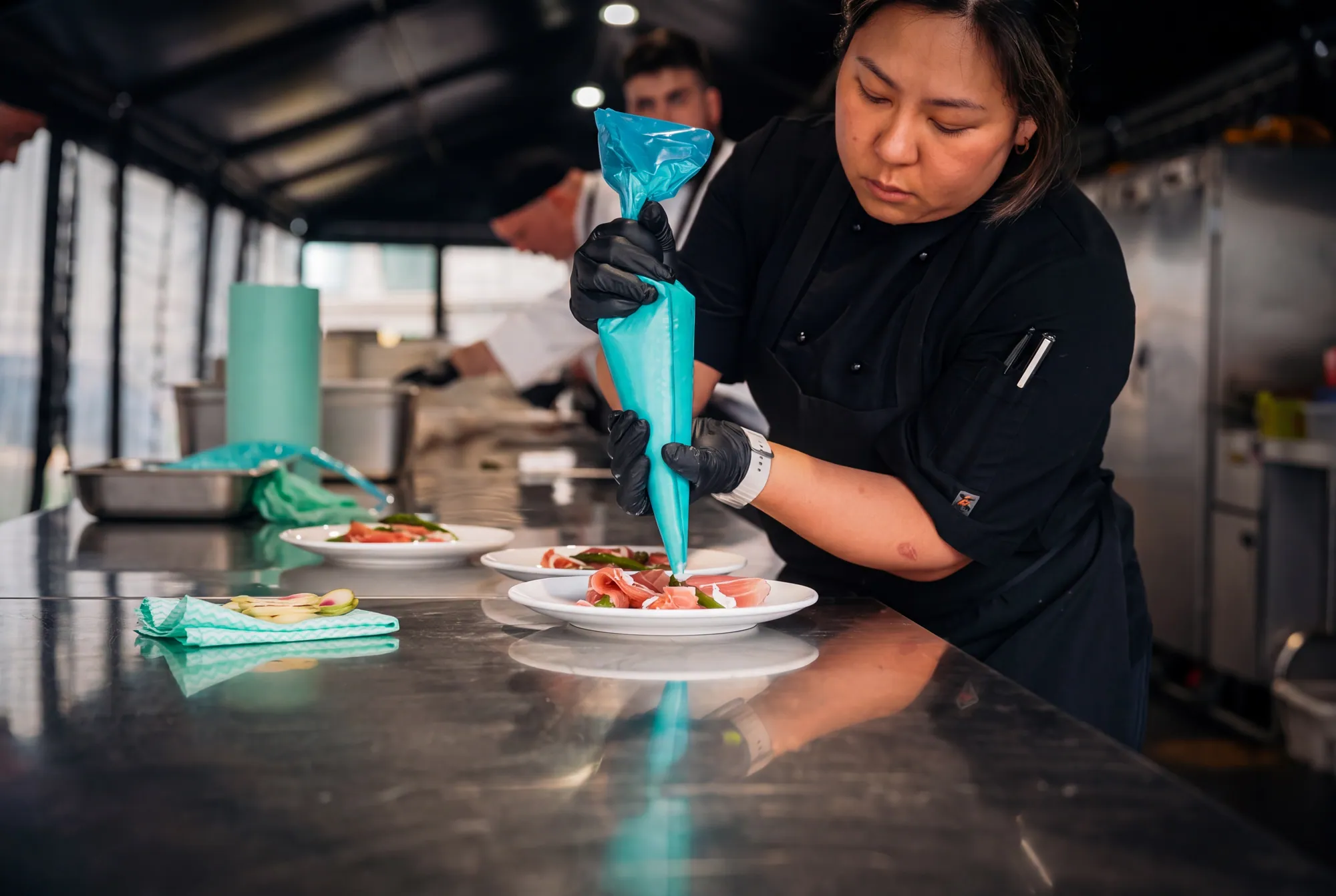 Chef piping onto entrées at the pass