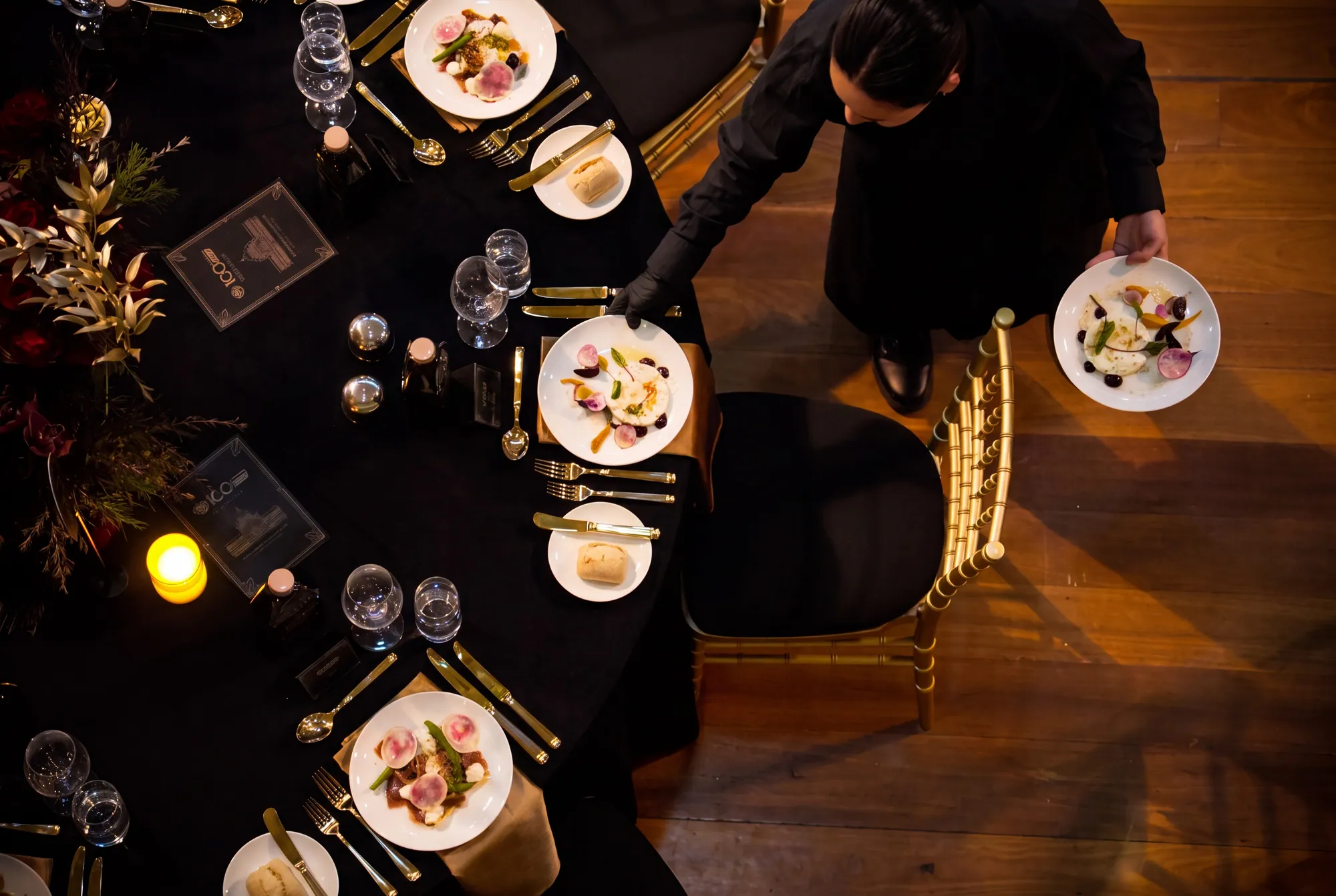 Overhead view of a waiter serving entrées at a gala table