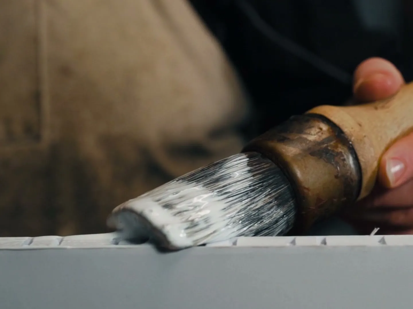 Close-up of a craftsman's hands brushing glue onto a book spine