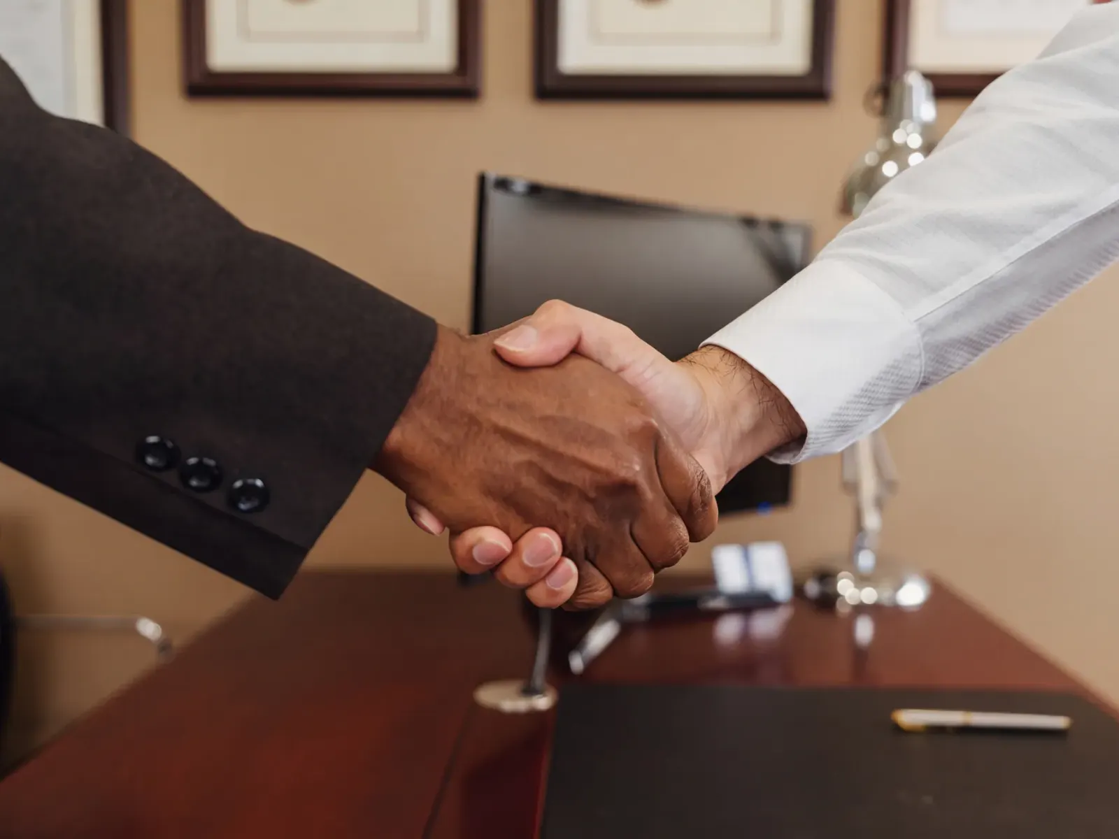 Close-up of a handshake across an office desk