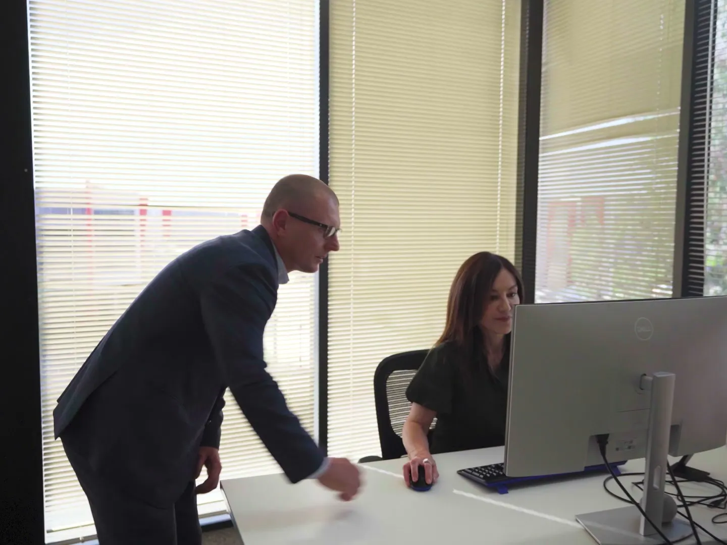 A manager checking in with a team member at her desk