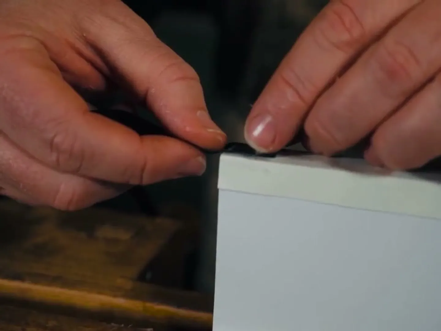 Close-up of hands finishing the edge of a hand-bound book