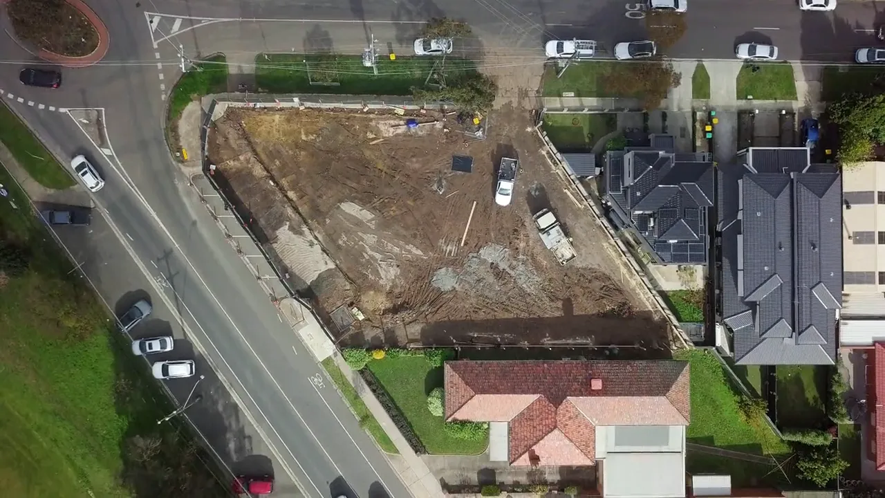 Top-down drone view of the site and the street corner