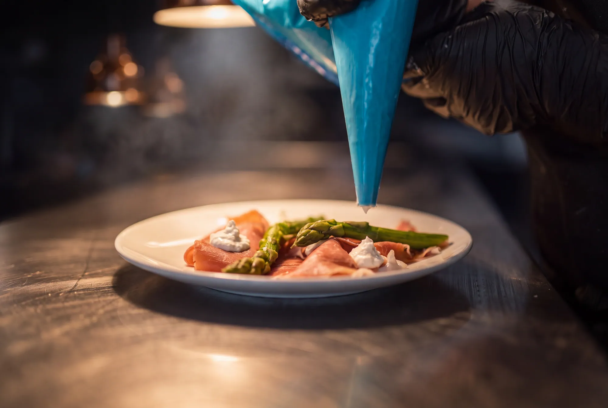 Piping bag finishing a prosciutto and asparagus entrée