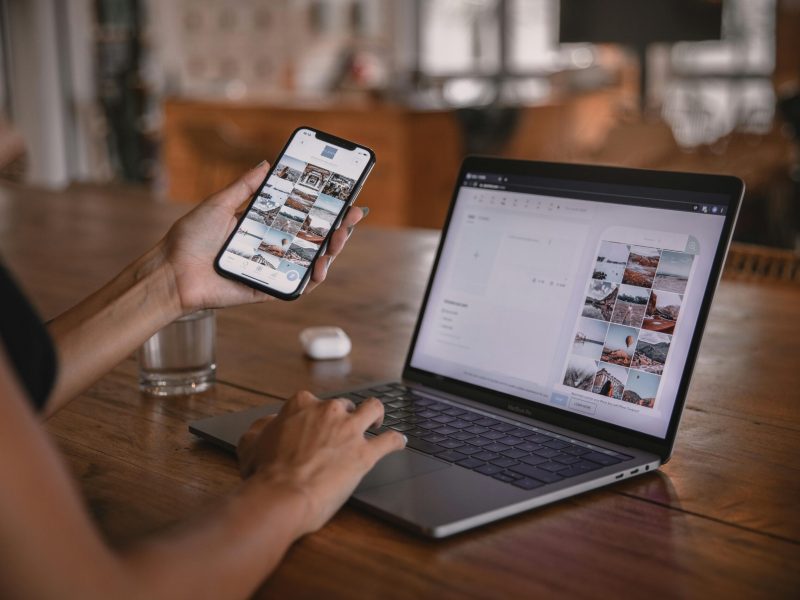 Woman edits social media content on phone and laptop at a cafe in Bali.